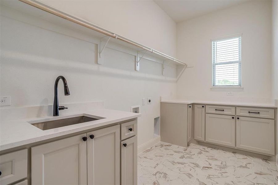 Laundry room featuring sink, cabinets, light tile patterned floors, hookup for an electric dryer, and washer hookup