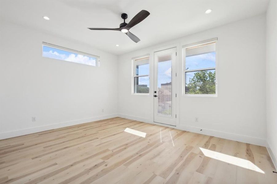 Unfurnished room featuring a wealth of natural light, ceiling fan, and light wood-type flooring