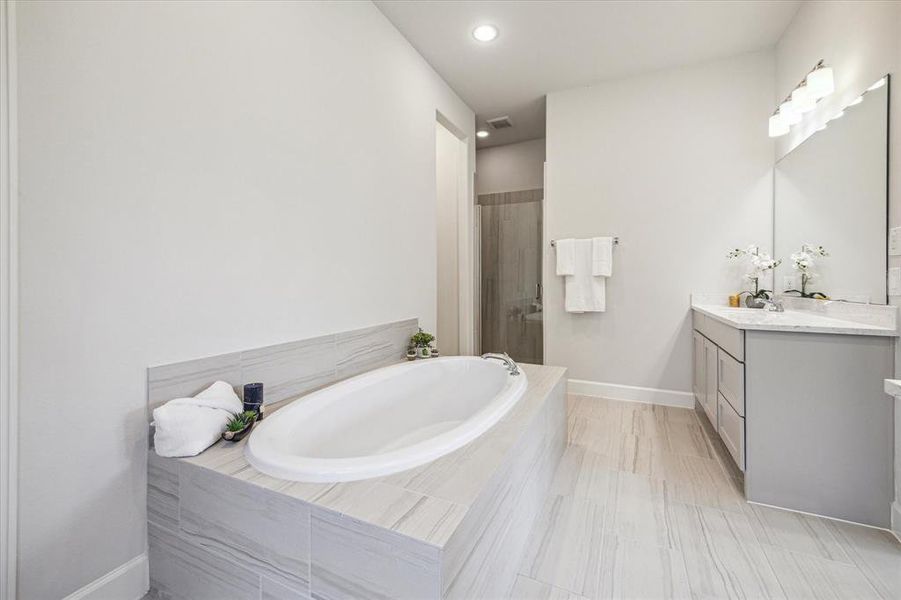 This primary bath offers a separate walk-in tile surround shower with a sitting bench, plus 2 walk in closets  making it a luxurious addition to a bathroom.