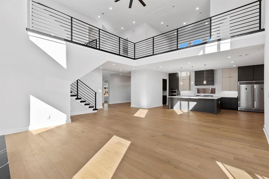 Unfurnished living room featuring light wood-type flooring and a high ceiling