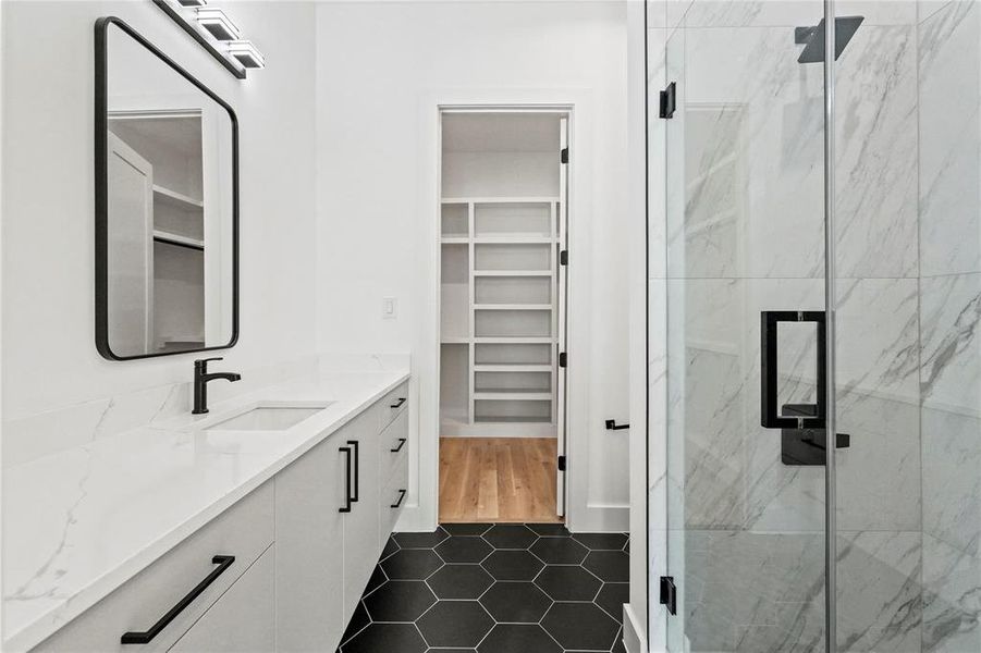 Bathroom featuring a shower with door, vanity, and tile patterned flooring