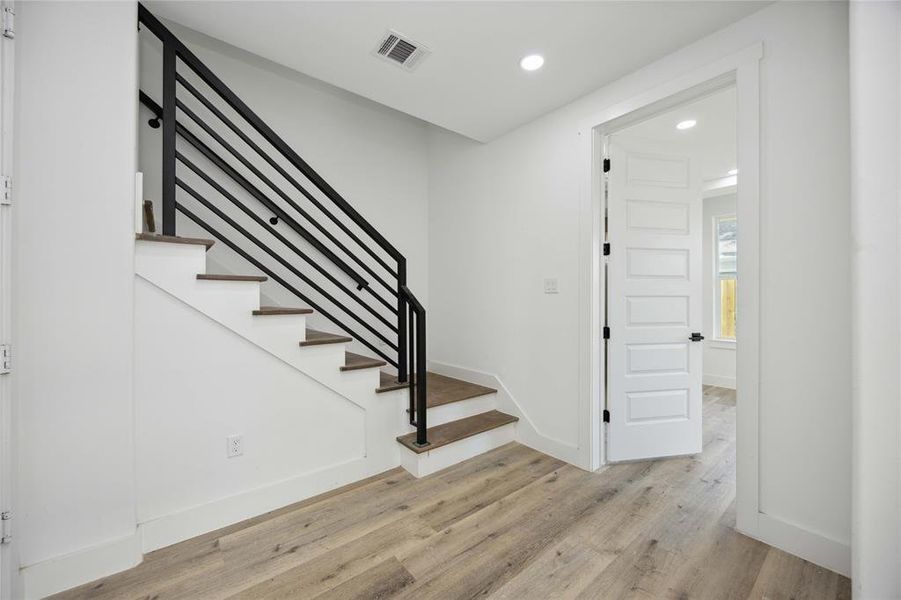 Stylish staircase with wooden treads and a sleek black metal railing leads to the second floor living space and kitchen.