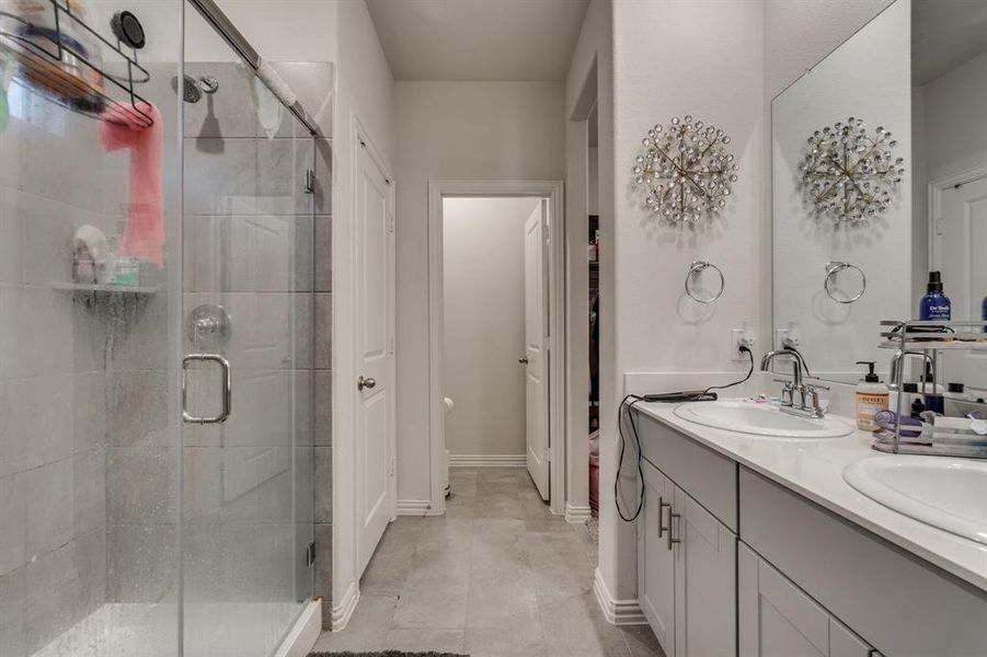 Bathroom featuring tile patterned flooring, vanity, and a shower with door