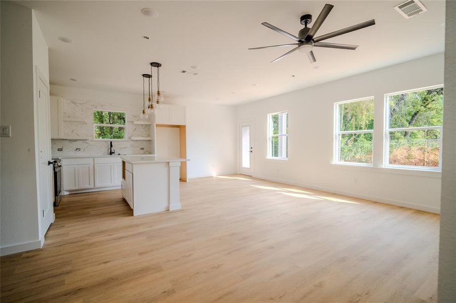 Kitchen with white cabinets, a center island, decorative light fixtures, light hardwood / wood-style floors, and ceiling fan