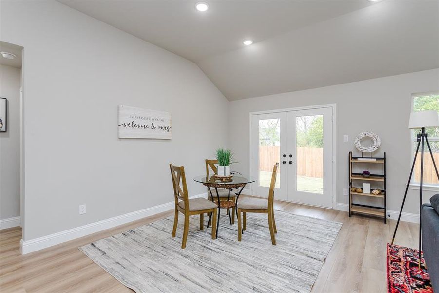 Dining room featuring light hardwood / wood-style flooring, french doors, and vaulted ceiling