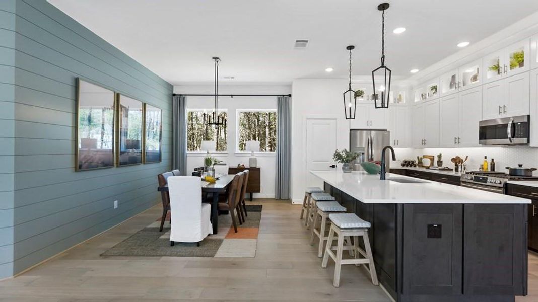 The dining room features a shiplap wall that extends from the family room, creating a cohesive and charming look. This design element adds a touch of rustic elegance, seamlessly connecting the two spaces and enhancing the overall aesthetic of the home.