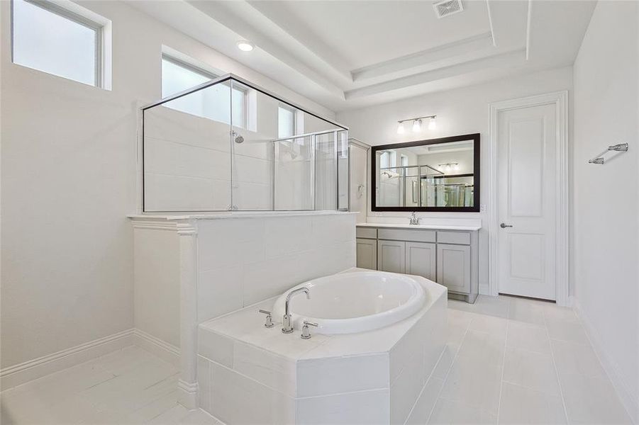 Bathroom with tile patterned floors, a tray ceiling, independent shower and bath, and vanity