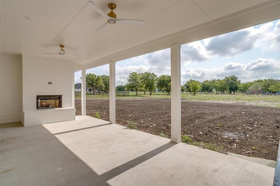 View of patio featuring an outdoor brick fireplace and ceiling fan