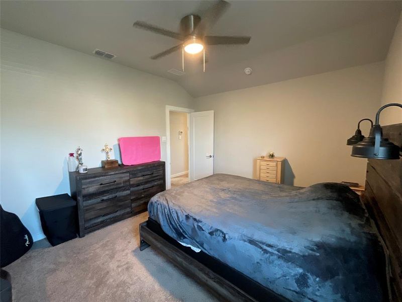 Carpeted bedroom with ceiling fan and vaulted ceiling