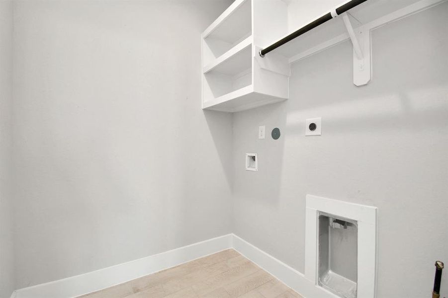 A spacious utility room with ample shelving for organization. It features connections for both gas and electric dryers, making it versatile and functional for all laundry needs.