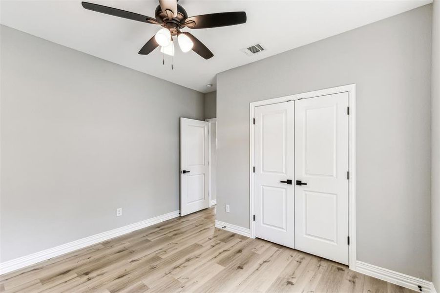 Unfurnished bedroom featuring light wood-type flooring, ceiling fan, and a closet