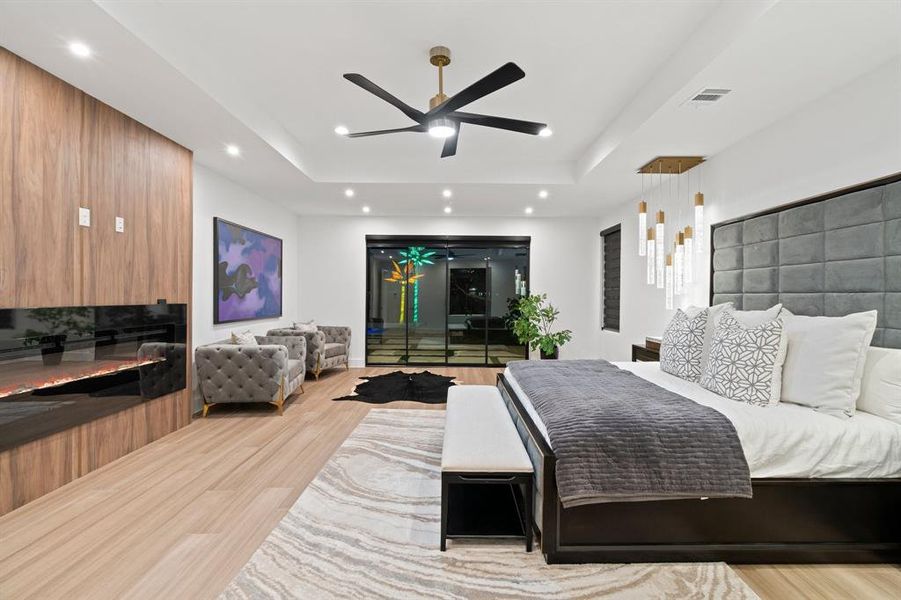 Bedroom featuring ceiling fan, a raised ceiling, and light hardwood / wood-style flooring