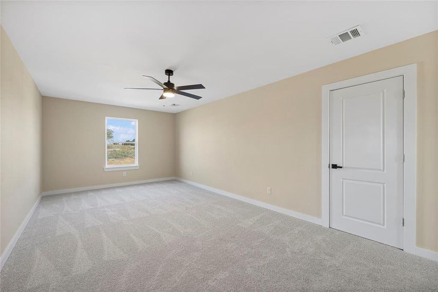 Carpeted spare room featuring ceiling fan