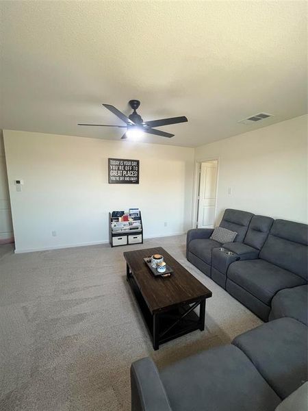 Carpeted living room featuring a textured ceiling and ceiling fan