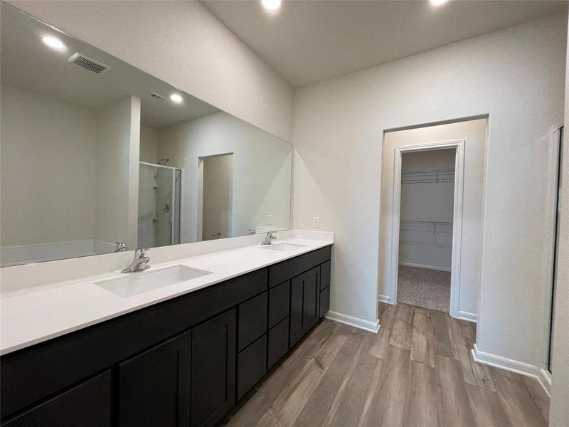 Bathroom featuring oversized vanity, an enclosed shower, hardwood / wood-style flooring, and double sink