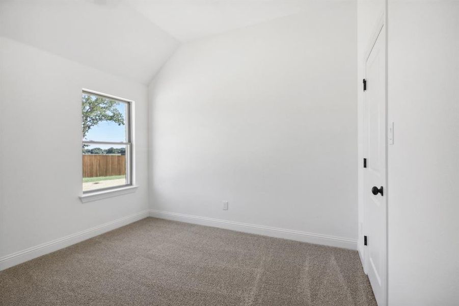 Carpeted spare room with vaulted ceiling