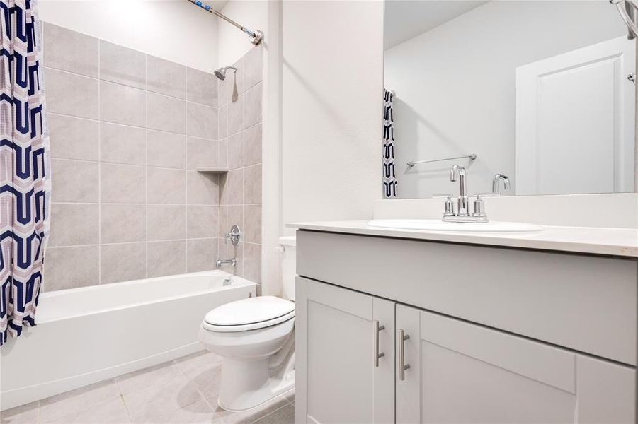 Full bathroom with vanity, tile patterned flooring, toilet, and shower / tub combo with curtain