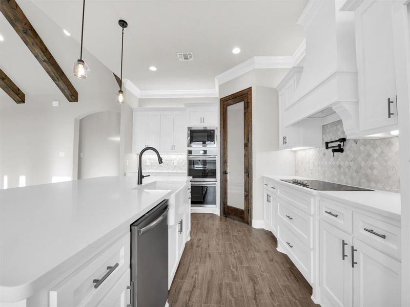 Kitchen featuring white cabinets, stainless steel appliances, tasteful backsplash, and custom exhaust hood