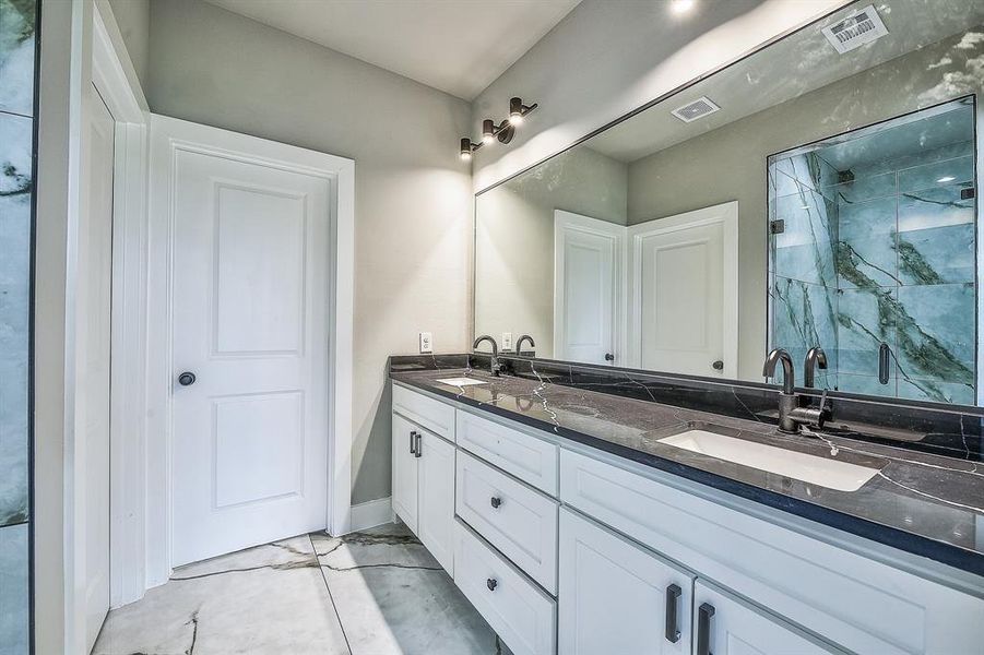 Bathroom with tile floors, a shower, and double sink vanity