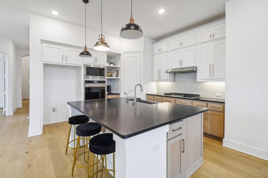 Kitchen featuring appliances with stainless steel finishes, white cabinetry, sink, and light wood-type flooring