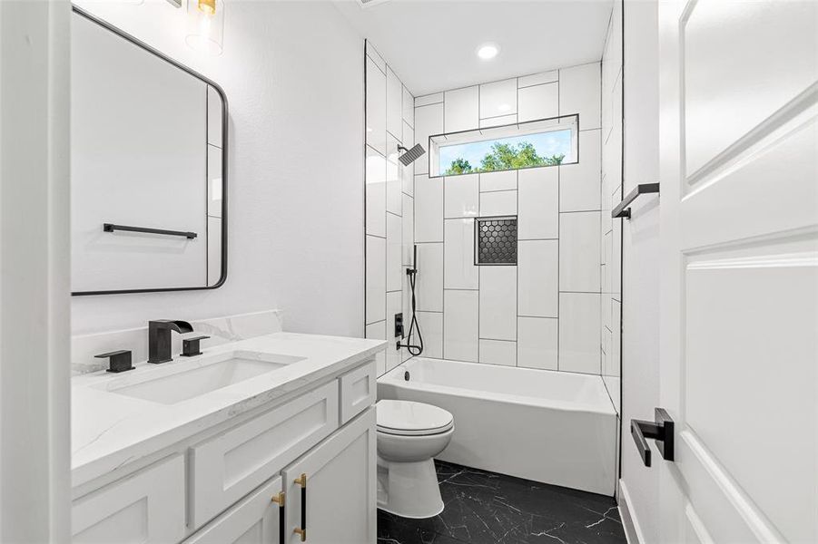 Full bathroom with tiled shower / bath combo, vanity, and toilet