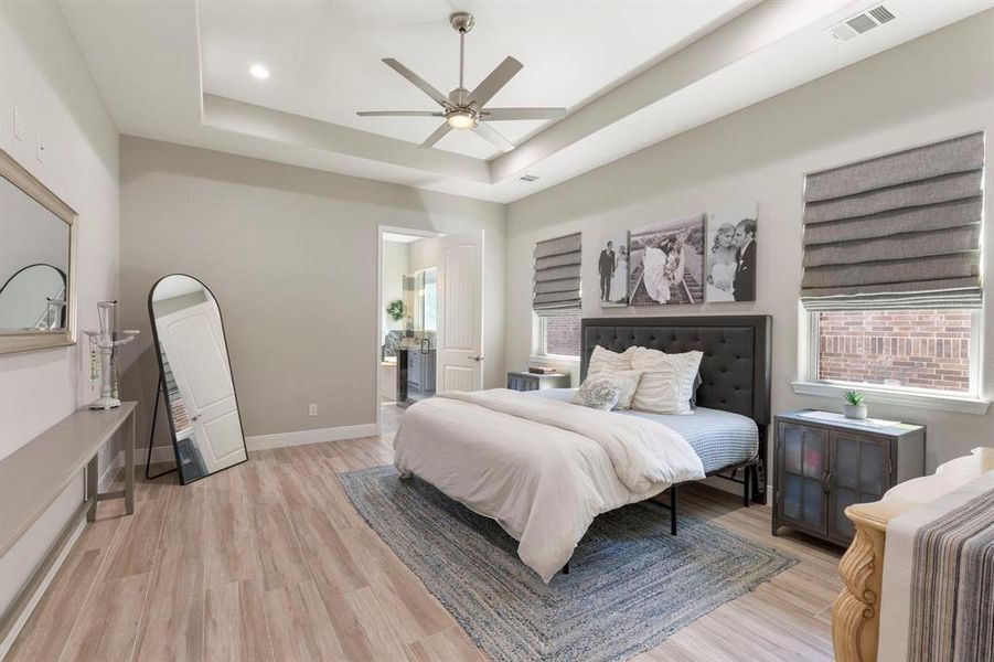 The primary bedroom has elevated features: automatic blinds, recessed ceiling, plenty of lighting, modern fan, and tile floors in warm neautral tones.