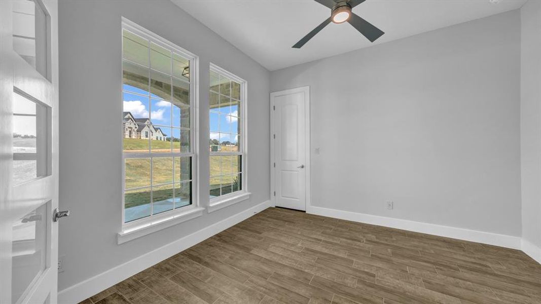 Spare room with ceiling fan with notable chandelier and wood-type flooring