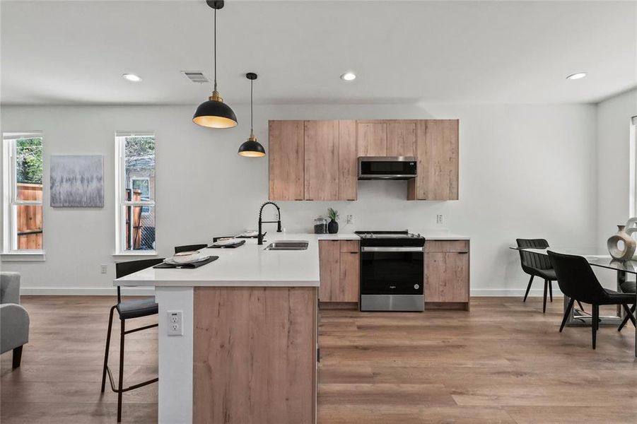 Kitchen featuring hardwood / wood-style floors, sink, stainless steel appliances, and decorative light fixtures