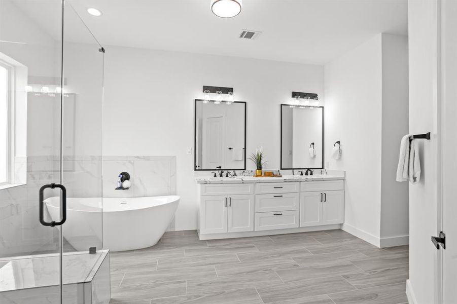 Spa-like primary en-suite features quartz countertops, ceramic tiles, double sinks, black framed mirrors, and plenty of high end lighting.