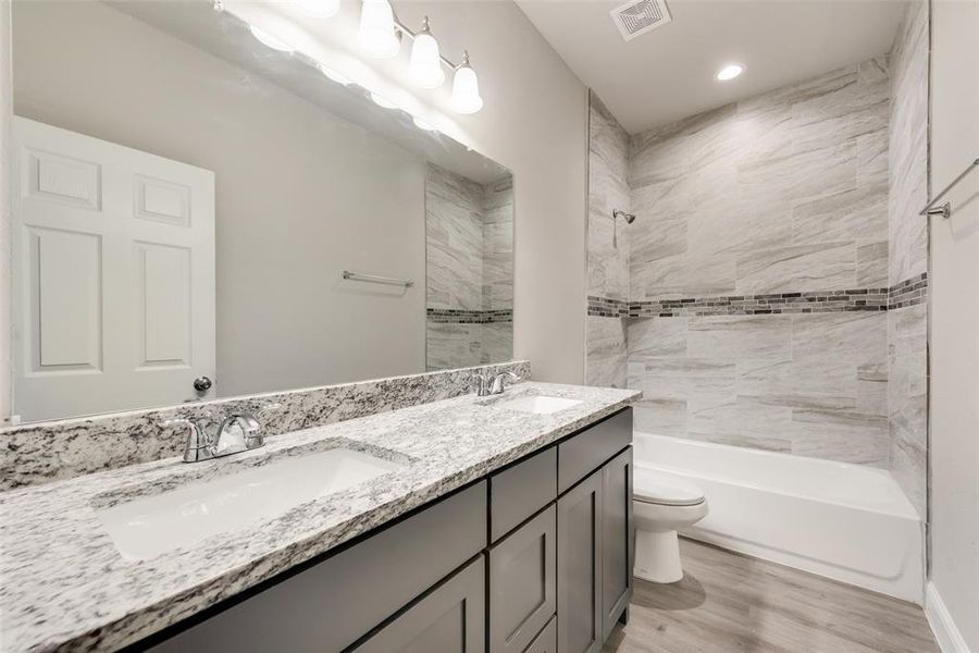 Full bathroom with hardwood / wood-style floors, vanity, toilet, and tiled shower / bath