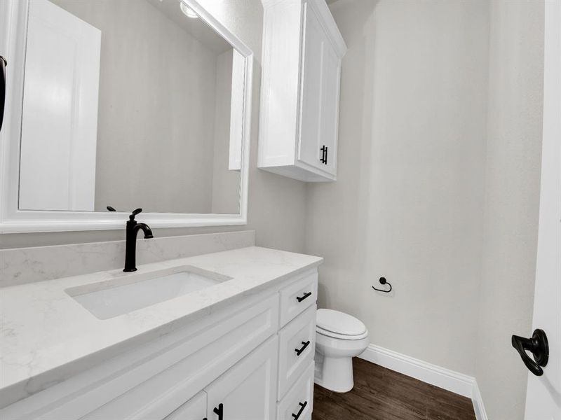 Bathroom featuring hardwood / wood-style flooring, vanity, and toilet