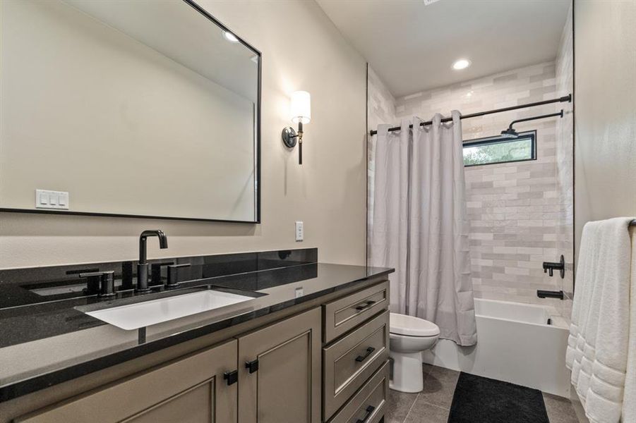 Full bathroom with vanity, tile patterned flooring, toilet, decorative backsplash, and shower / bath combo