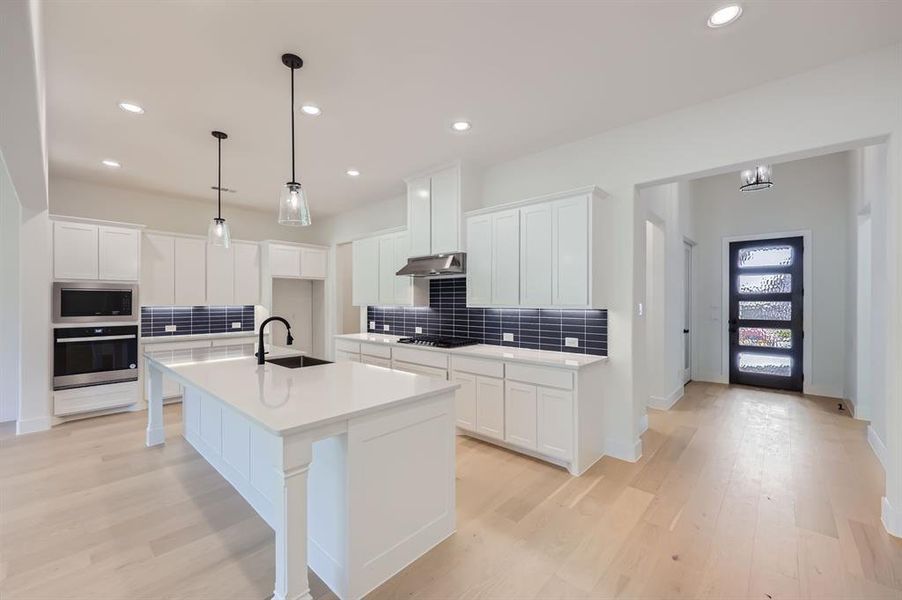 Kitchen featuring white cabinetry, stainless steel appliances, sink, and a kitchen island with sink