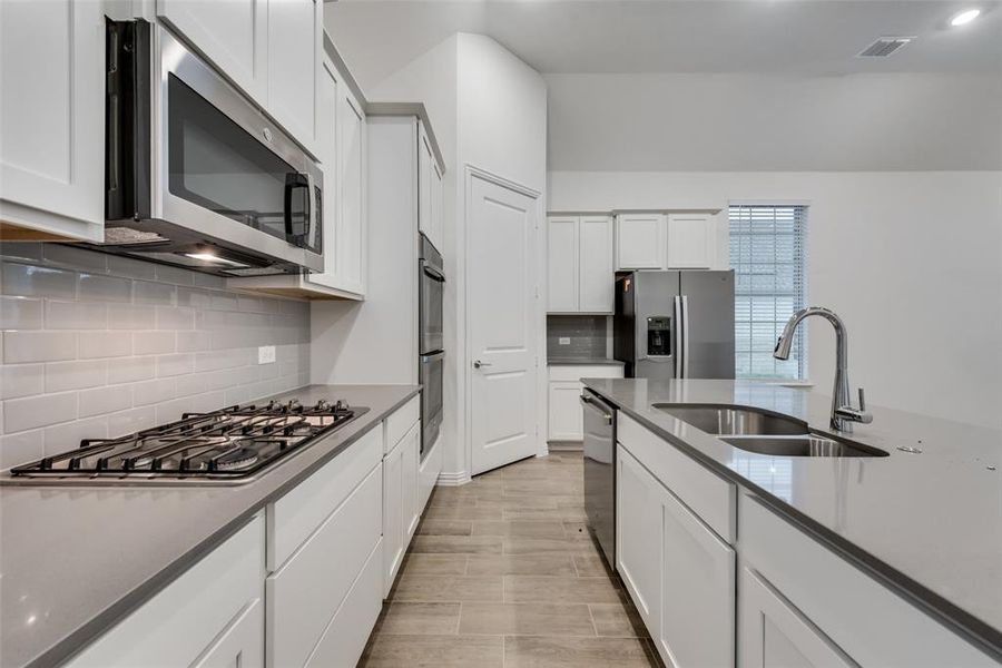 Kitchen featuring white cabinetry, sink, tasteful backsplash, and stainless steel appliances