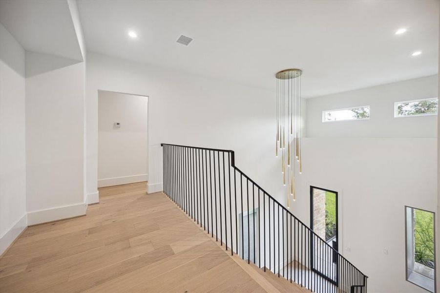 At the top of the stairs, the wide landing offers space for displaying artwork or for a quiet reading spot. Well-placed windows and a stunning chandelier provide perfect lighting, day or night.