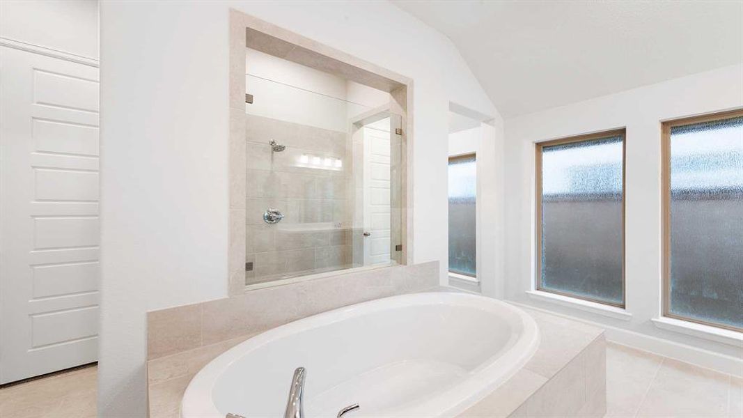 Bathroom featuring shower with separate bathtub, tile patterned floors, and lofted ceiling