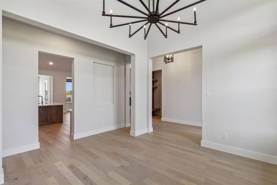 Empty room with a chandelier and light hardwood / wood-style flooring