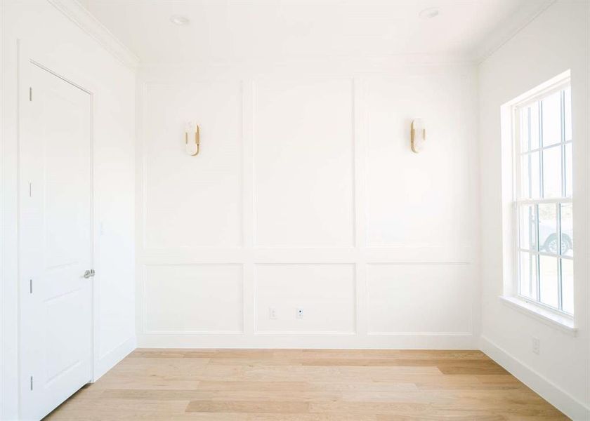 Empty room featuring light wood-type flooring, a healthy amount of sunlight, and crown molding