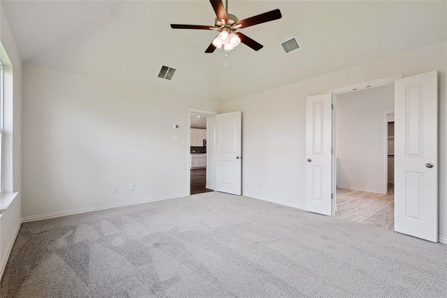 Unfurnished bedroom with a spacious closet, high vaulted ceiling, ceiling fan, and light colored carpet