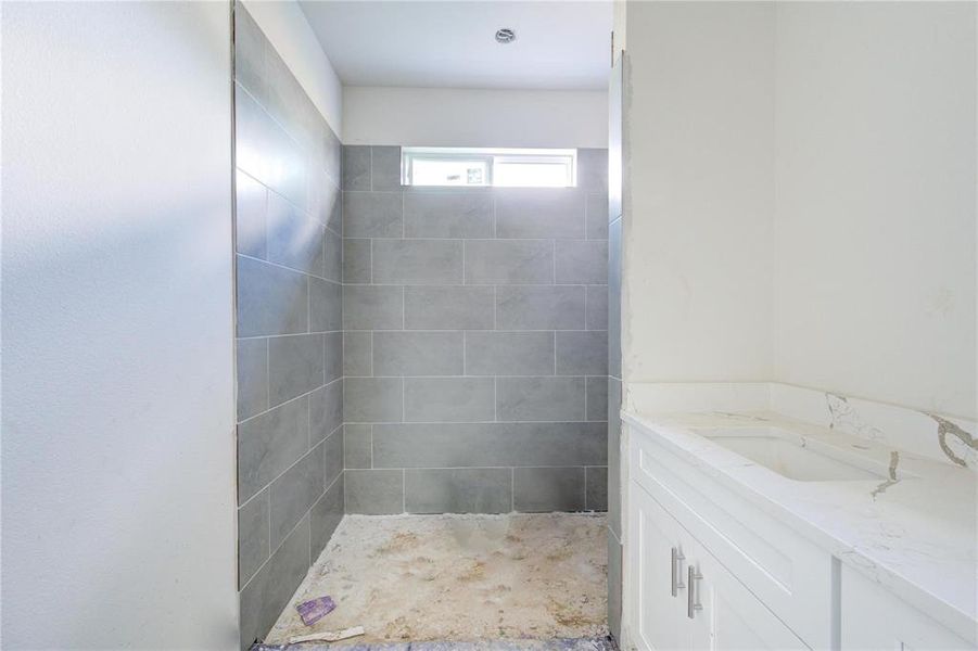 With modern tiling and a clean, minimalist design, this bathroom offers a glimpse of its future potential. The generous shower area and spacious vanity provide the foundation for a relaxing retreat. **This image is from another Saratoga Home - Artemis floorplan.**