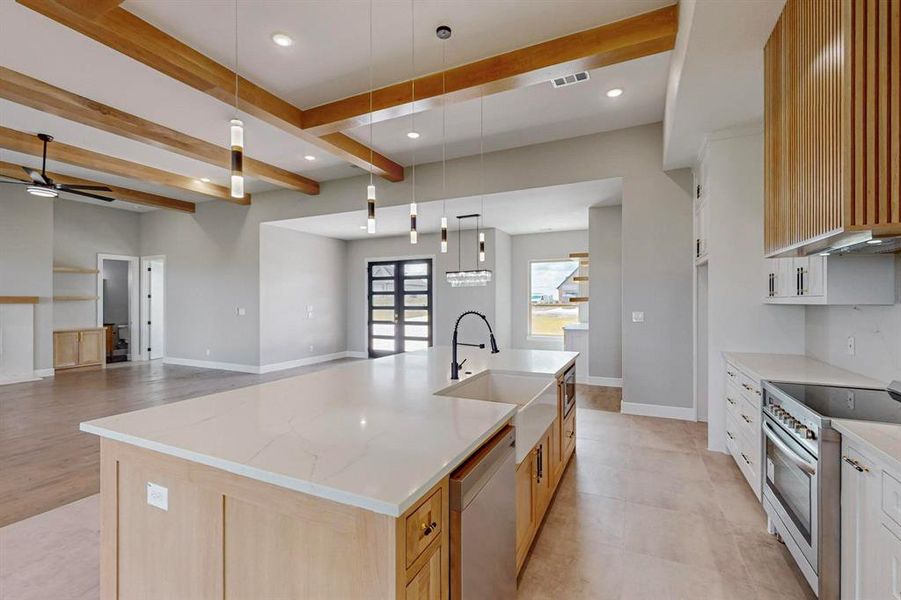 Kitchen featuring appliances with stainless steel finishes, beamed ceiling, ceiling fan, and a spacious island