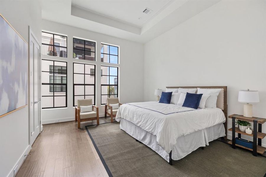 Bathed in natural light, this primary bedroom exudes elegance with its custom coffer ceiling, 4" hardwood flooring, and stunning custom routed edge ceiling detail