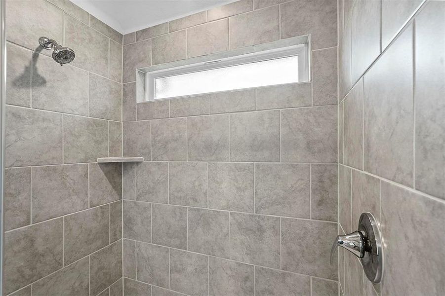Bathroom featuring tiled shower and a healthy amount of sunlight