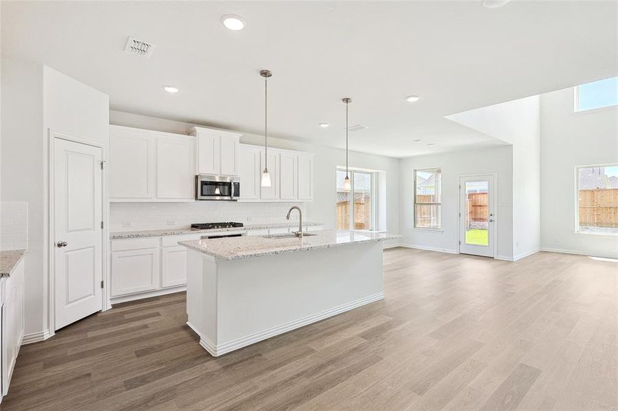 Kitchen with decorative backsplash, sink, range, white cabinets, and hardwood / wood-style flooring