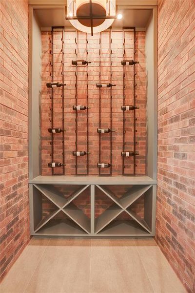 The Wine Room is insulated and wired for climate control featuring beautiful brick accent walls, built-in iron and wood display storage, a full glass door and on-trend light fixture.