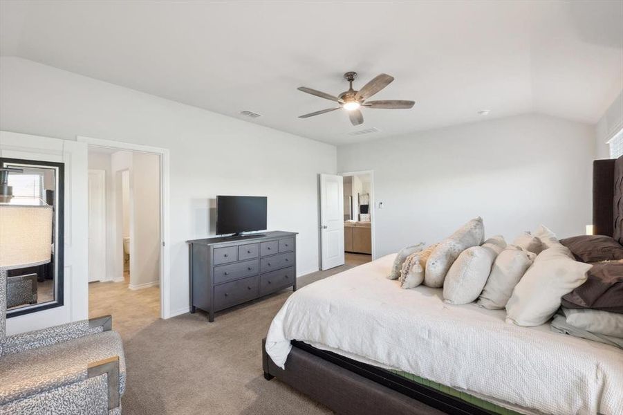 Carpeted bedroom with connected bathroom, lofted ceiling, and ceiling fan