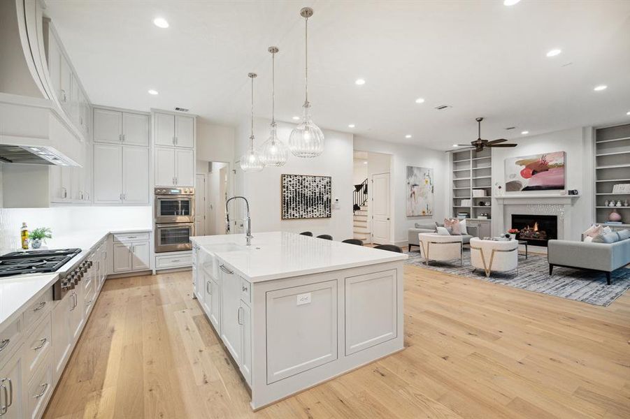 Island Kitchen with Slab Quartz Counters, 2 x 5 Picket Mosaic Tile Backsplash finished in a Vertical Pattern and Under-Cabinet Lighting.