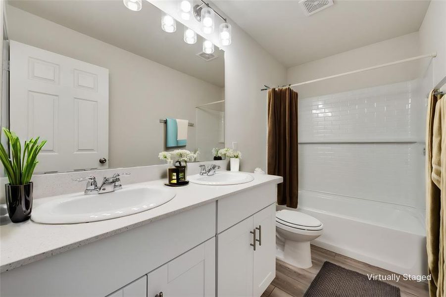 Full bathroom featuring LVP flooring, shower / bath combination, toilet, and dual bowl vanity