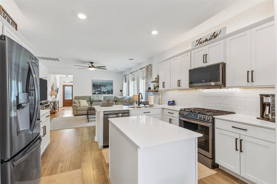 Kitchen with sink, kitchen peninsula, light hardwood / wood-style flooring, stainless steel appliances, and a center island