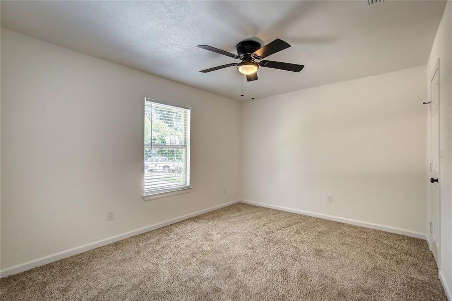 Carpeted second room featuring ceiling fan